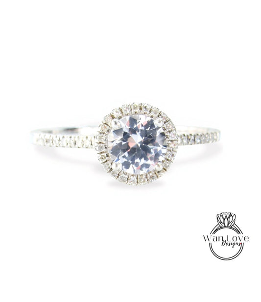 A close-up view of a diamond engagement ring with a large central diamond surrounded by smaller diamonds, set in a halo of smaller diamonds.