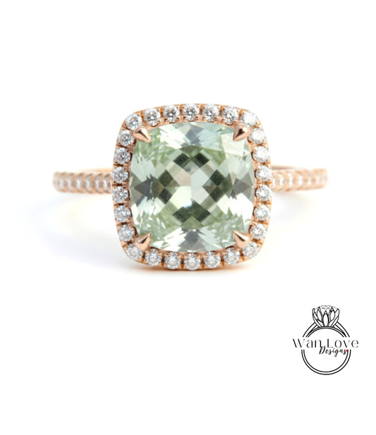 A ring featuring a large, square-cut green gemstone surrounded by a halo of smaller diamonds set in a rose gold band.