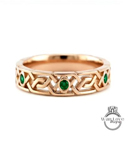 A gold ring with a Celtic knot design and two green gemstones.