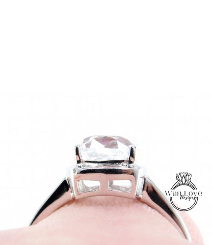 A close-up view of a silver engagement ring with a large, clear gemstone set in the center.