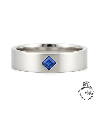 A silver ring with a blue gemstone, possibly a sapphire, set in the center.