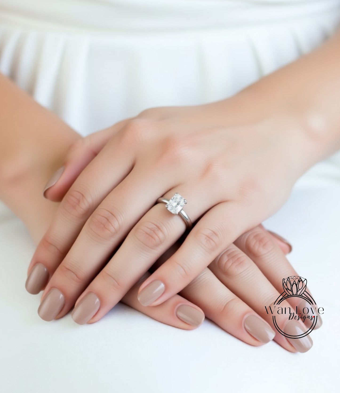 A close-up image of a person's hands with a diamond engagement ring on the ring finger.