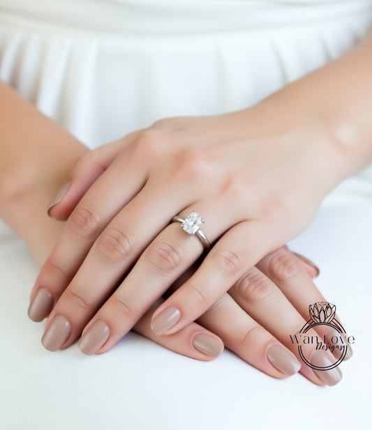 A close-up image of a person's hands with a diamond engagement ring on the ring finger.