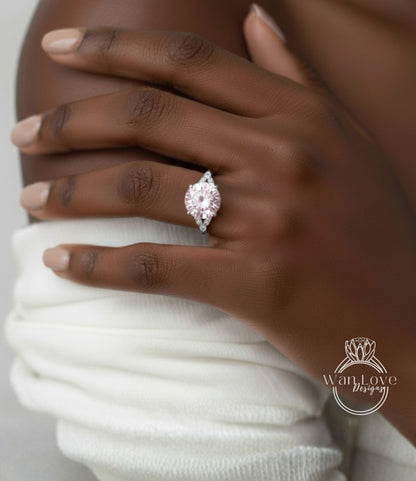 A close-up of a hand wearing a large, pink diamond engagement ring.