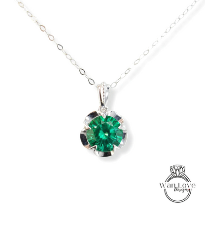 A silver necklace with a large, green gemstone pendant.