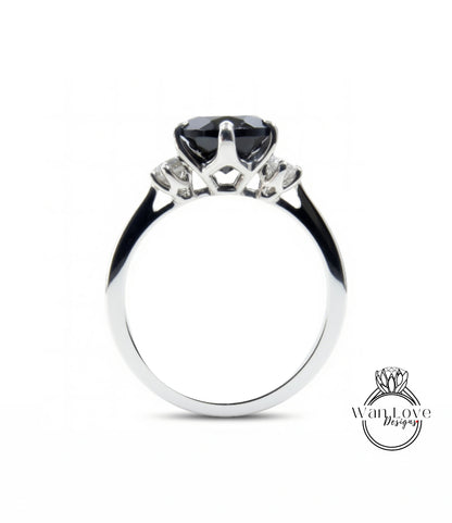 A silver engagement ring with a large black gemstone, possibly a diamond, set in the center.
