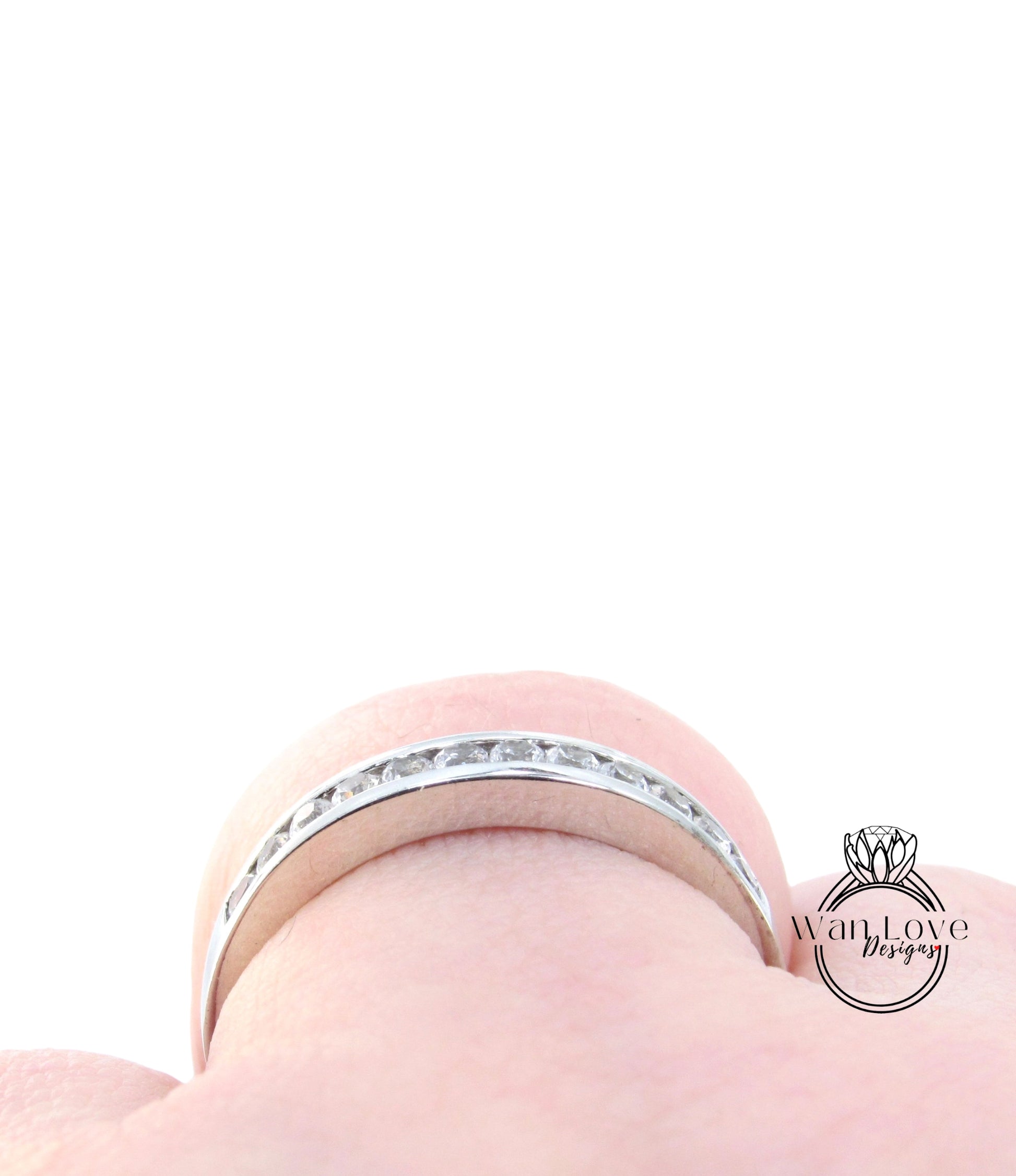 A close-up view of a silver ring with a row of small diamonds set in it, worn on a person's finger.