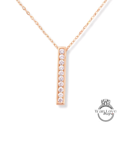 A delicate gold necklace with a single, rectangular pendant featuring a row of small diamonds.