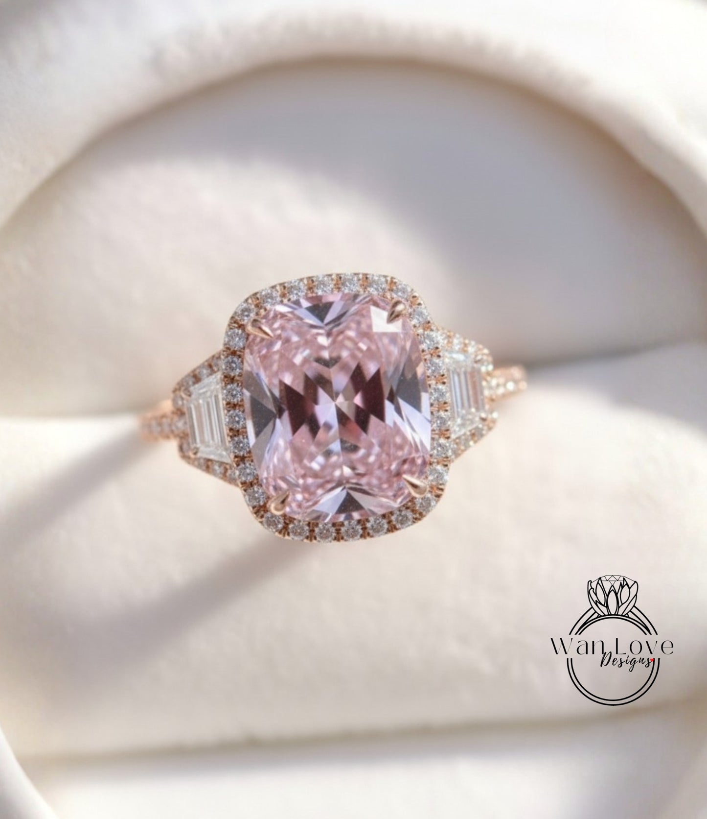 A beautiful pink gemstone ring with a halo of smaller diamonds around the center stone, displayed on a white background.