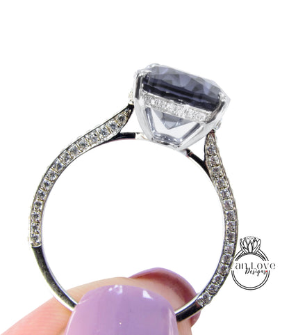 A close-up of a person's hand holding a silver ring with a large, clear gemstone set in the center.