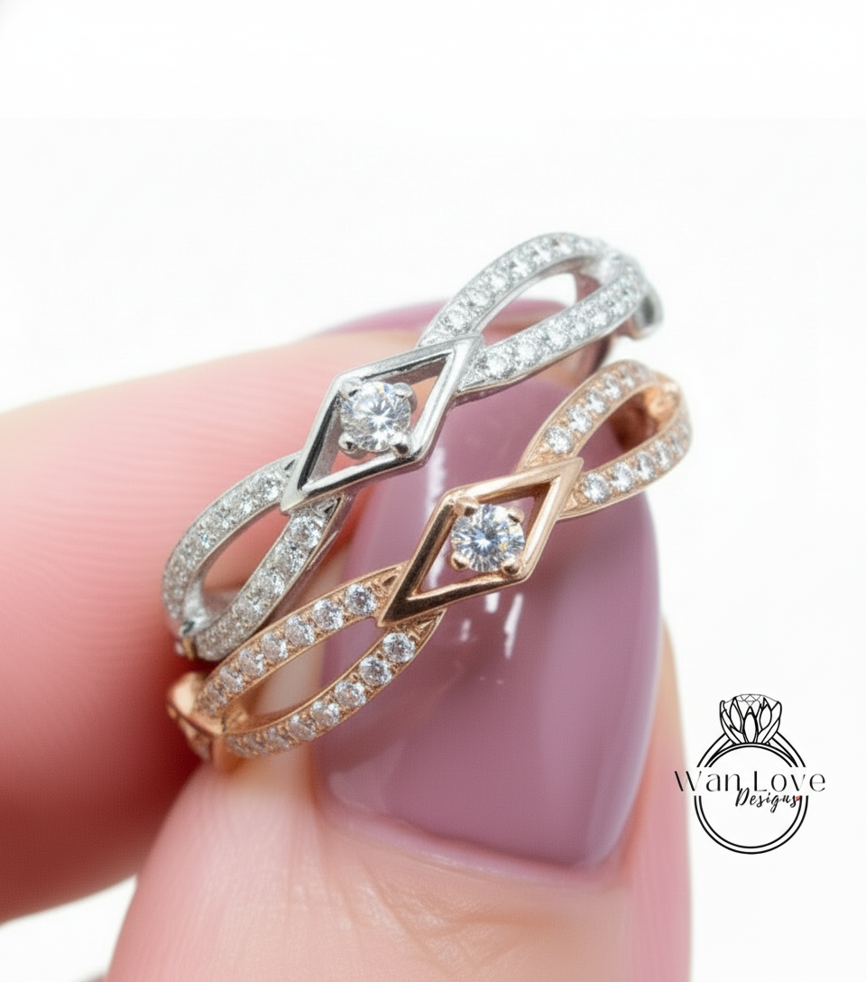 A close-up of a person's hand wearing a ring with two diamond-encrusted designs.
