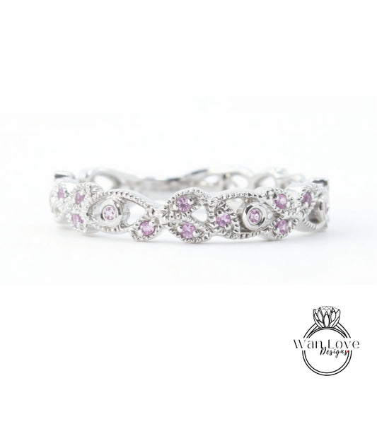A silver ring with a decorative floral design and small purple gemstones.