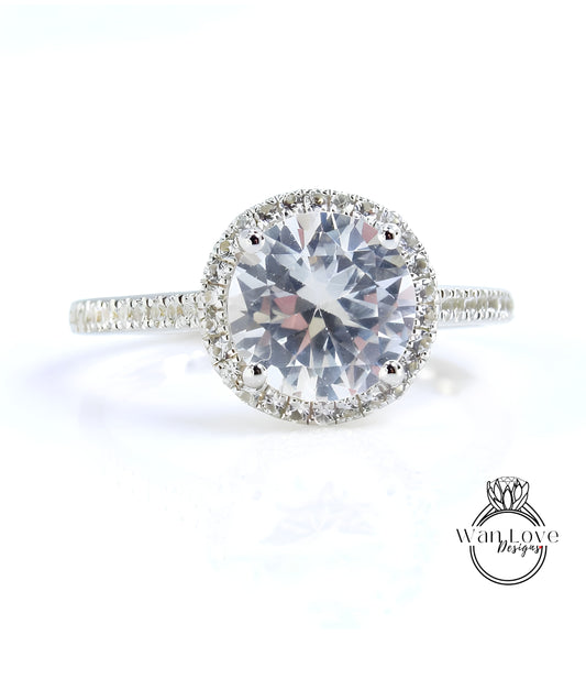 A close-up view of a diamond engagement ring with a large, round brilliant-cut diamond set in a halo of smaller diamonds.
