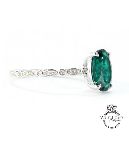 A silver ring with a large oval-shaped green gemstone, possibly a diamond, set in the center.
