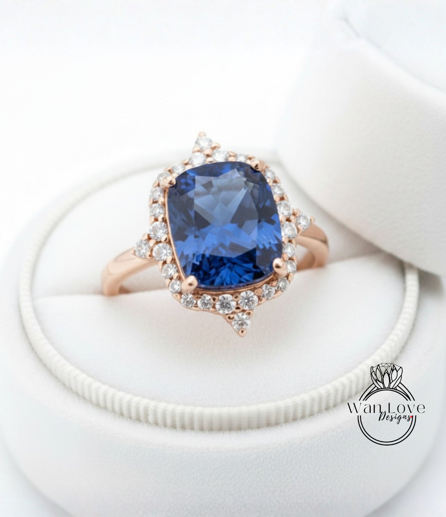 A stunning blue gemstone ring with a halo of sparkling diamonds, displayed in a white jewelry box.