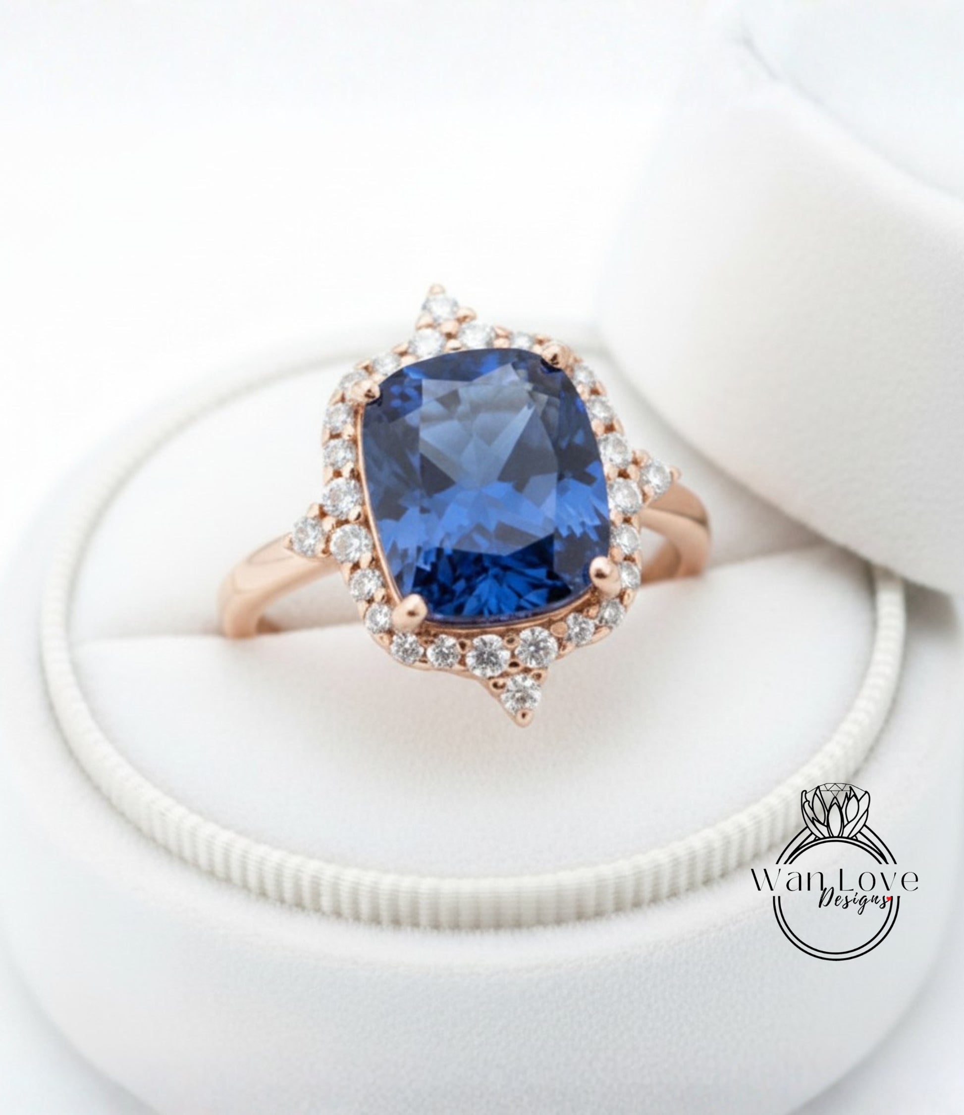A stunning blue gemstone ring with a halo of sparkling diamonds, displayed in a white jewelry box.