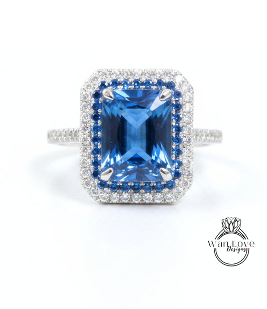 A stunning blue gemstone ring with a halo of diamonds around it, set in a silver band.