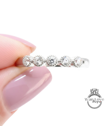 A close-up image of a person's hand holding a ring with a row of diamonds on it.