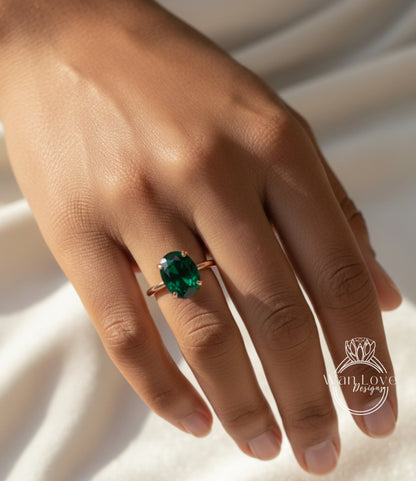 A close-up of a person's hand wearing a ring with a large, green gemstone.