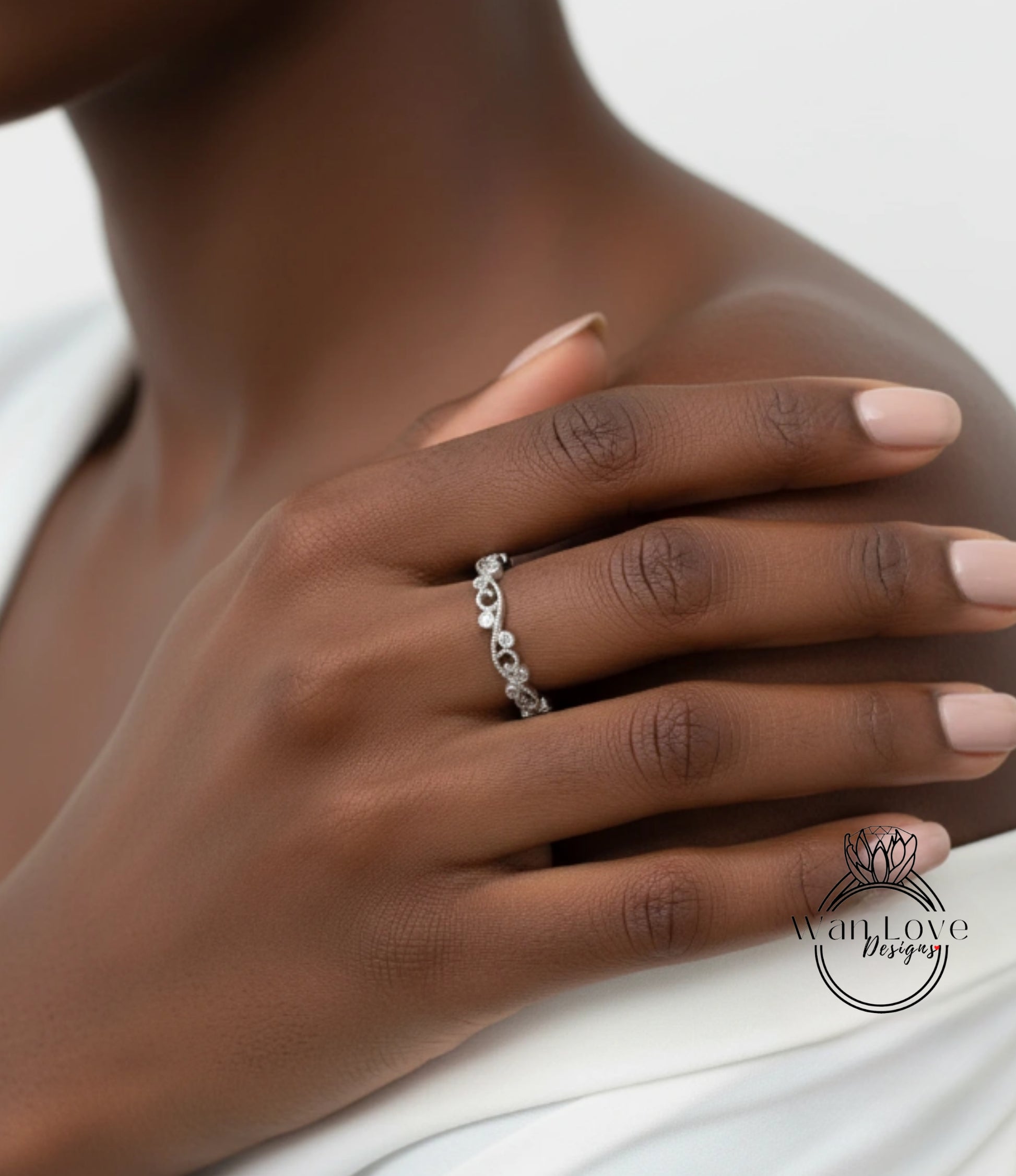 A close-up of a person's hand wearing a silver ring with a floral design.