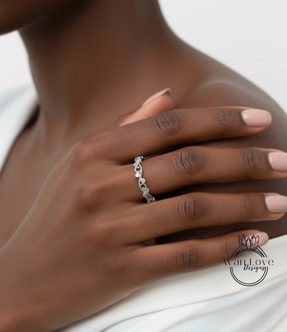 A close-up of a person's hand wearing a silver ring with a floral design.