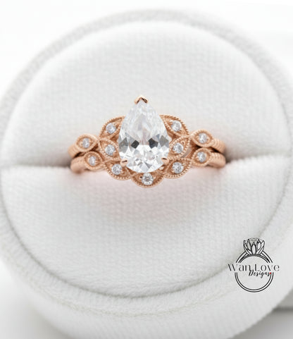 A close-up image of a gold ring with a large pear-shaped diamond set in the center, surrounded by smaller diamonds.