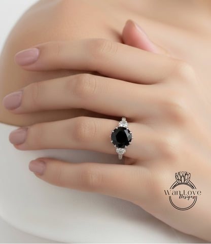 A close-up of a person's hand wearing a ring with a large black gemstone.