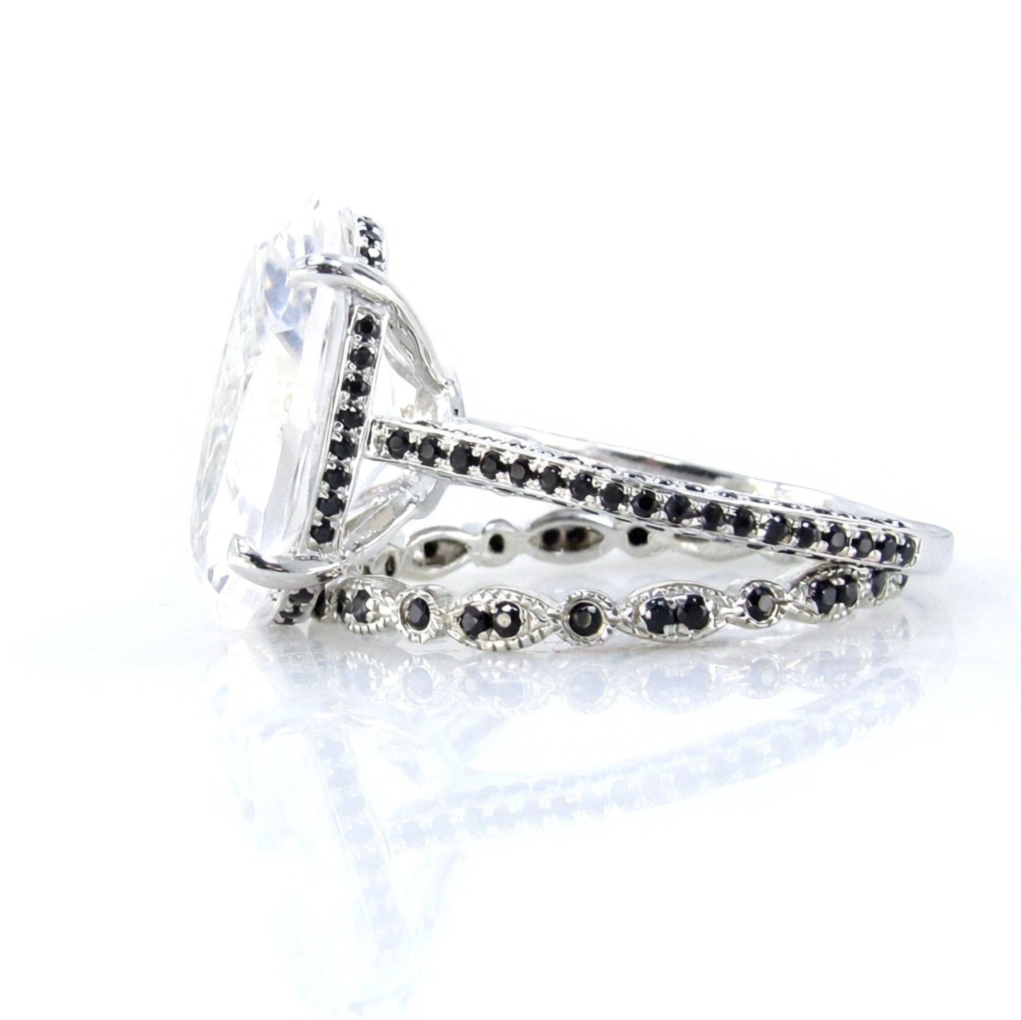 A close-up view of a silver ring with a large, clear gemstone set in the center, surrounded by smaller black gemstones.