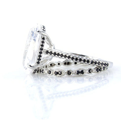 A close-up view of a silver ring with a large, clear gemstone set in the center, surrounded by smaller black gemstones.