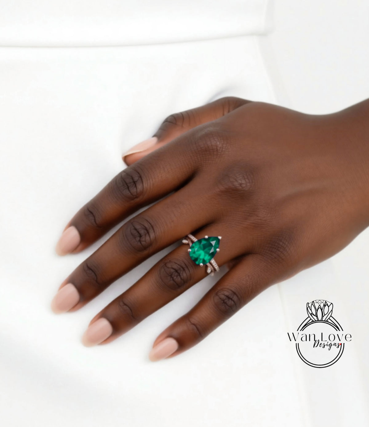 A close-up of a hand wearing a ring with a large green gemstone.