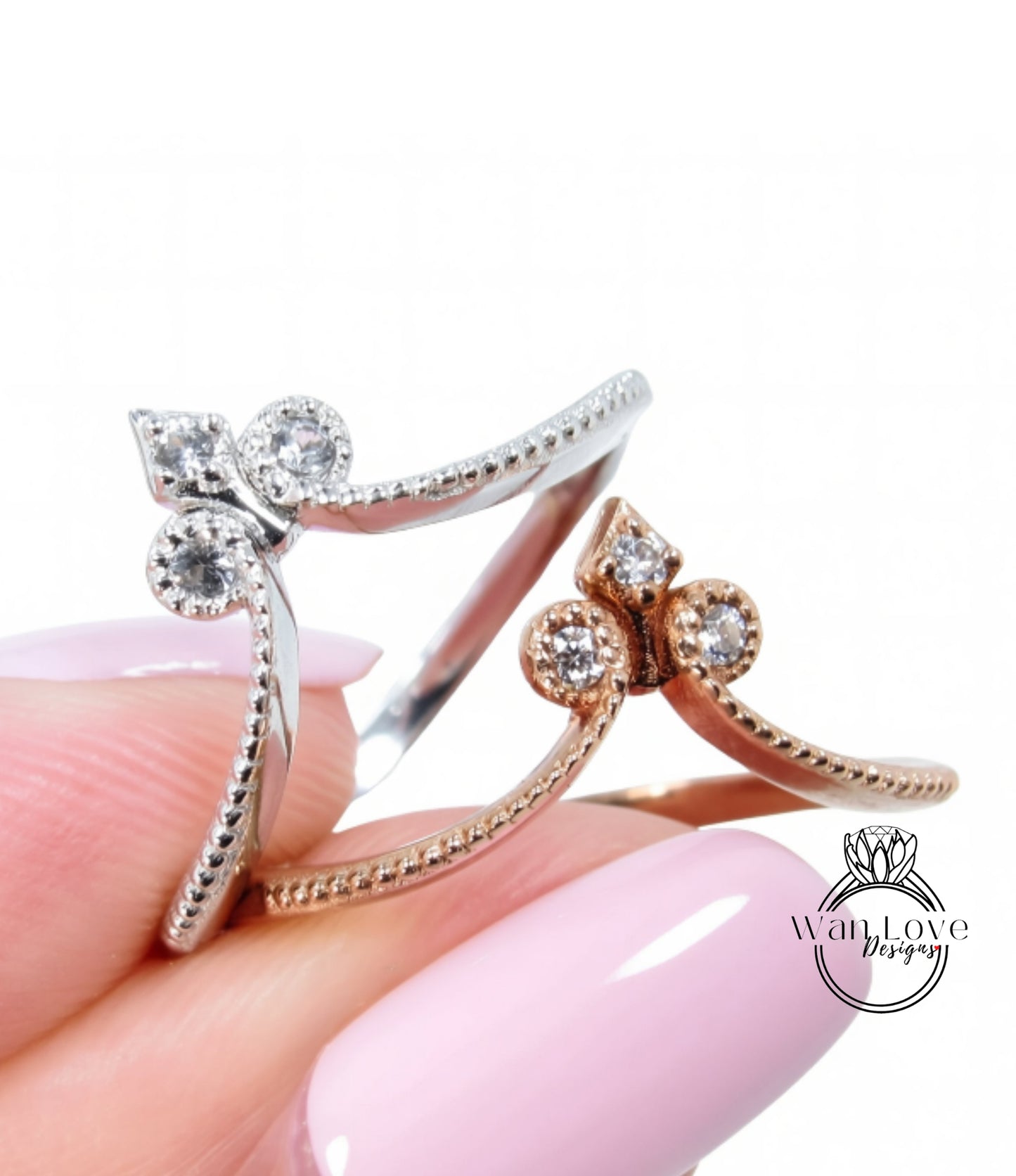 A close-up image of a person's hand holding two rings, one silver and one gold, with small diamonds set in the center.