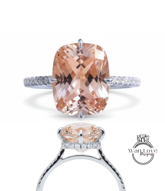 A stunning engagement ring featuring a large, oval-shaped, peach-colored gemstone set in a silver band with small diamonds.