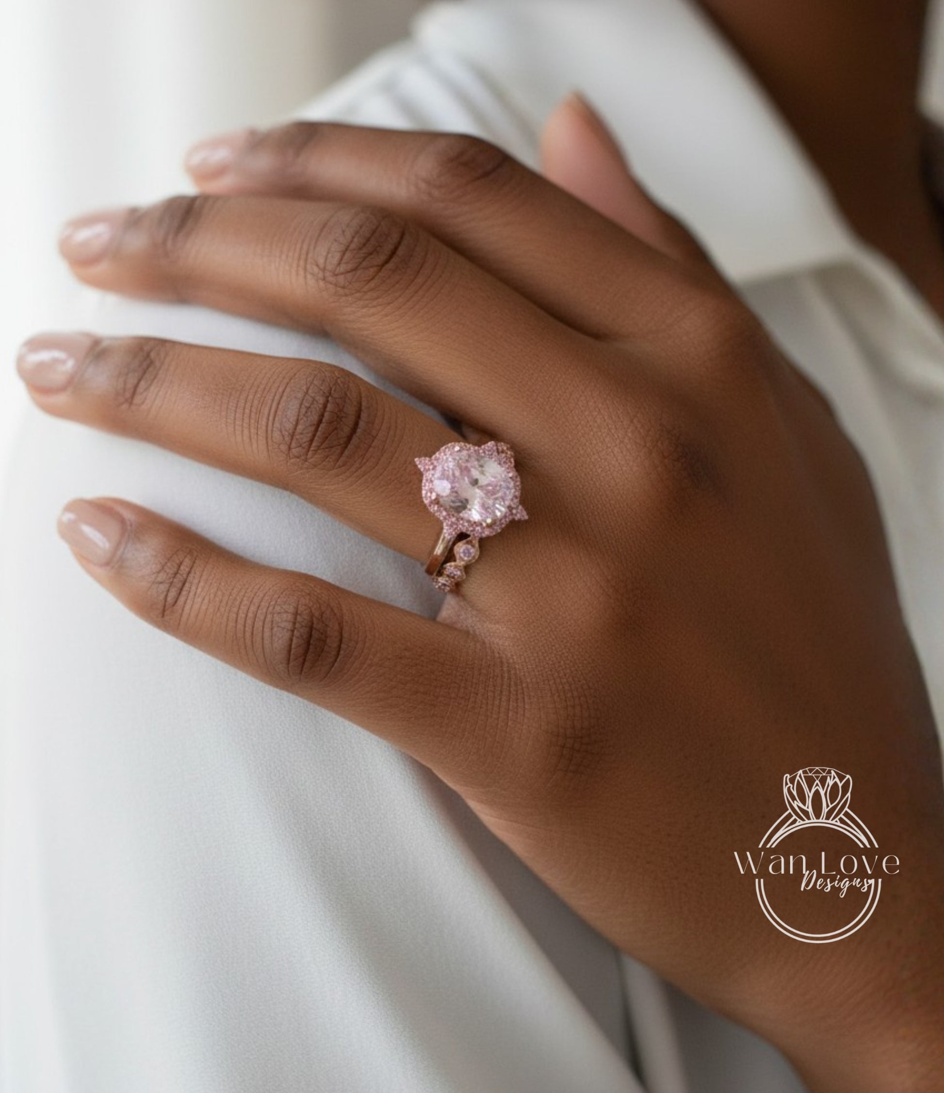 A close-up of a person's hand wearing a pink diamond ring on the ring finger.
