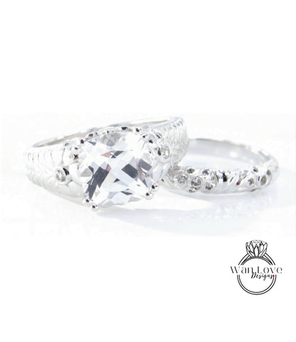 A close-up view of a large, clear gemstone set in a silver ring, with a smaller ring on top.