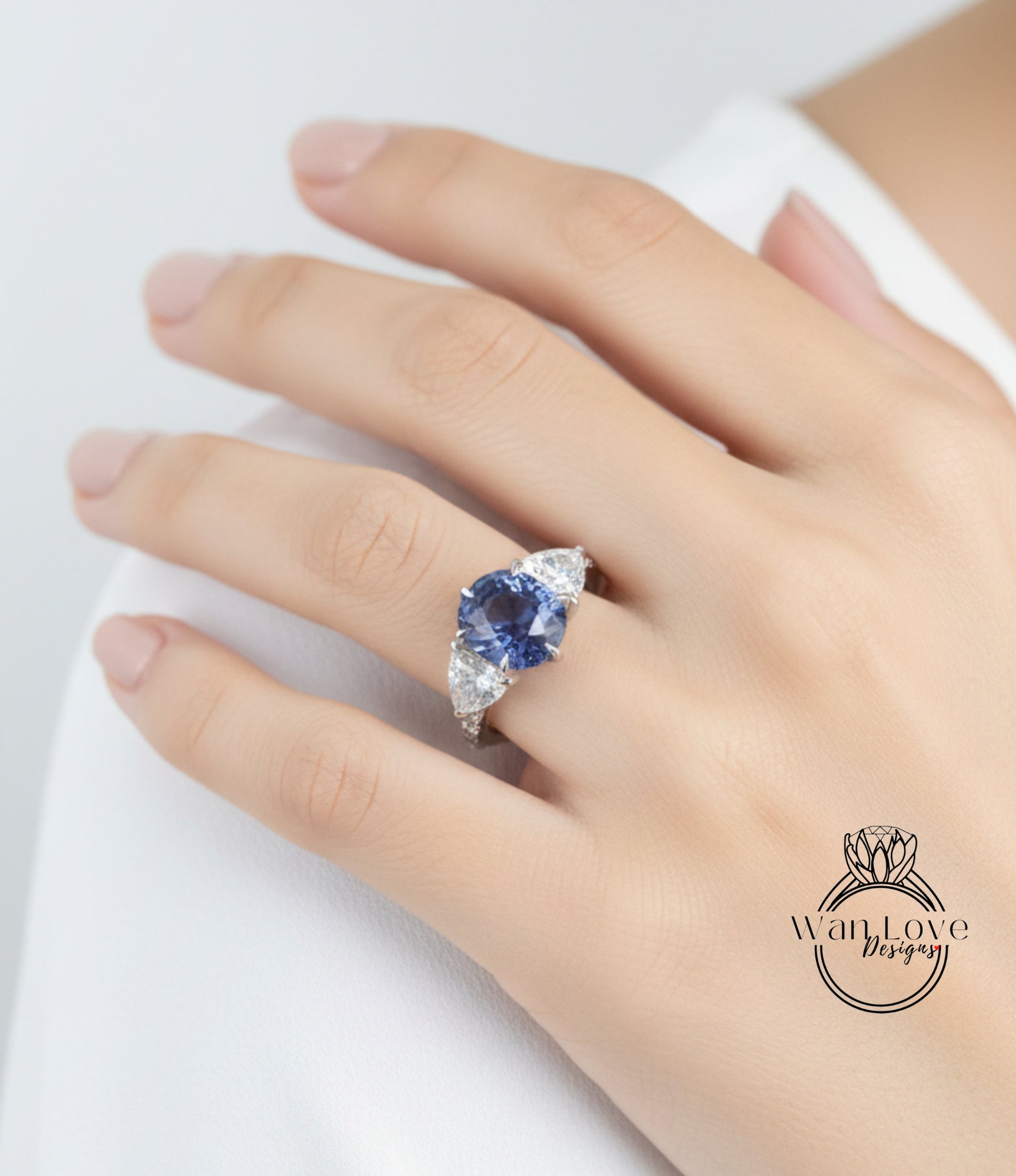 A close-up of a person's hand wearing a ring with a large blue gemstone.
