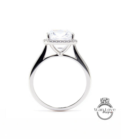 A silver engagement ring with a large, clear gemstone set in the center, surrounded by a halo of smaller diamonds.