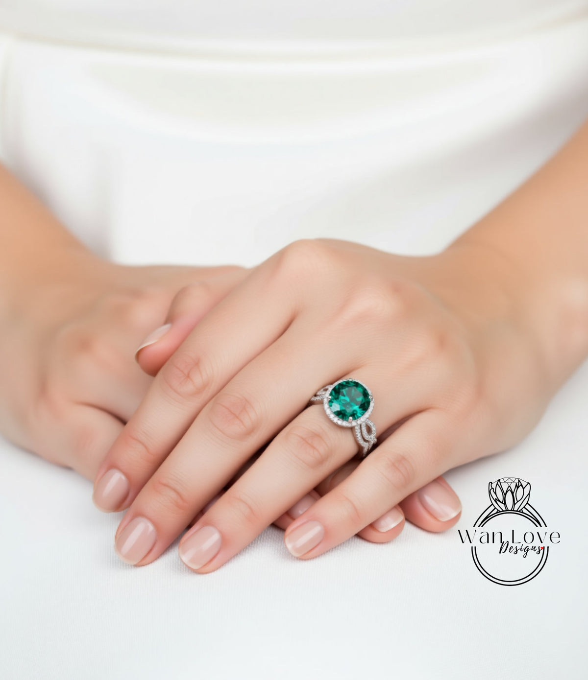 A close-up of a person's hands wearing a ring with a large green gemstone.