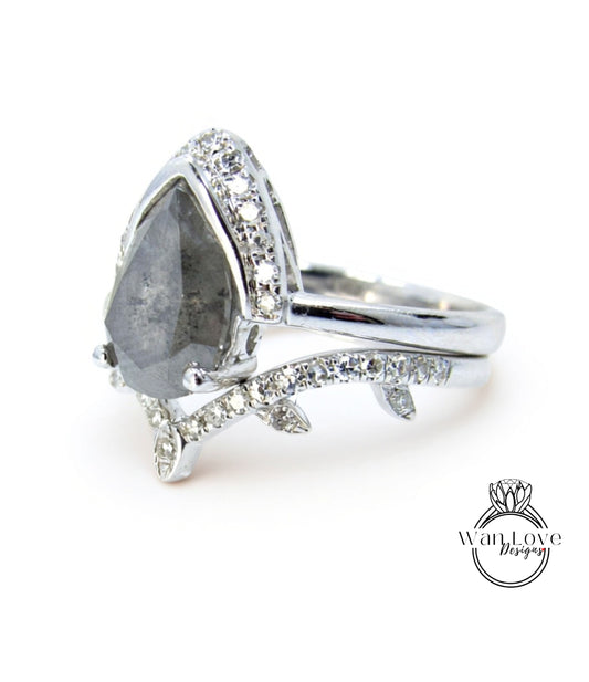 A silver ring with a large diamond as the centerpiece, surrounded by smaller diamonds and a leaf-shaped accent.