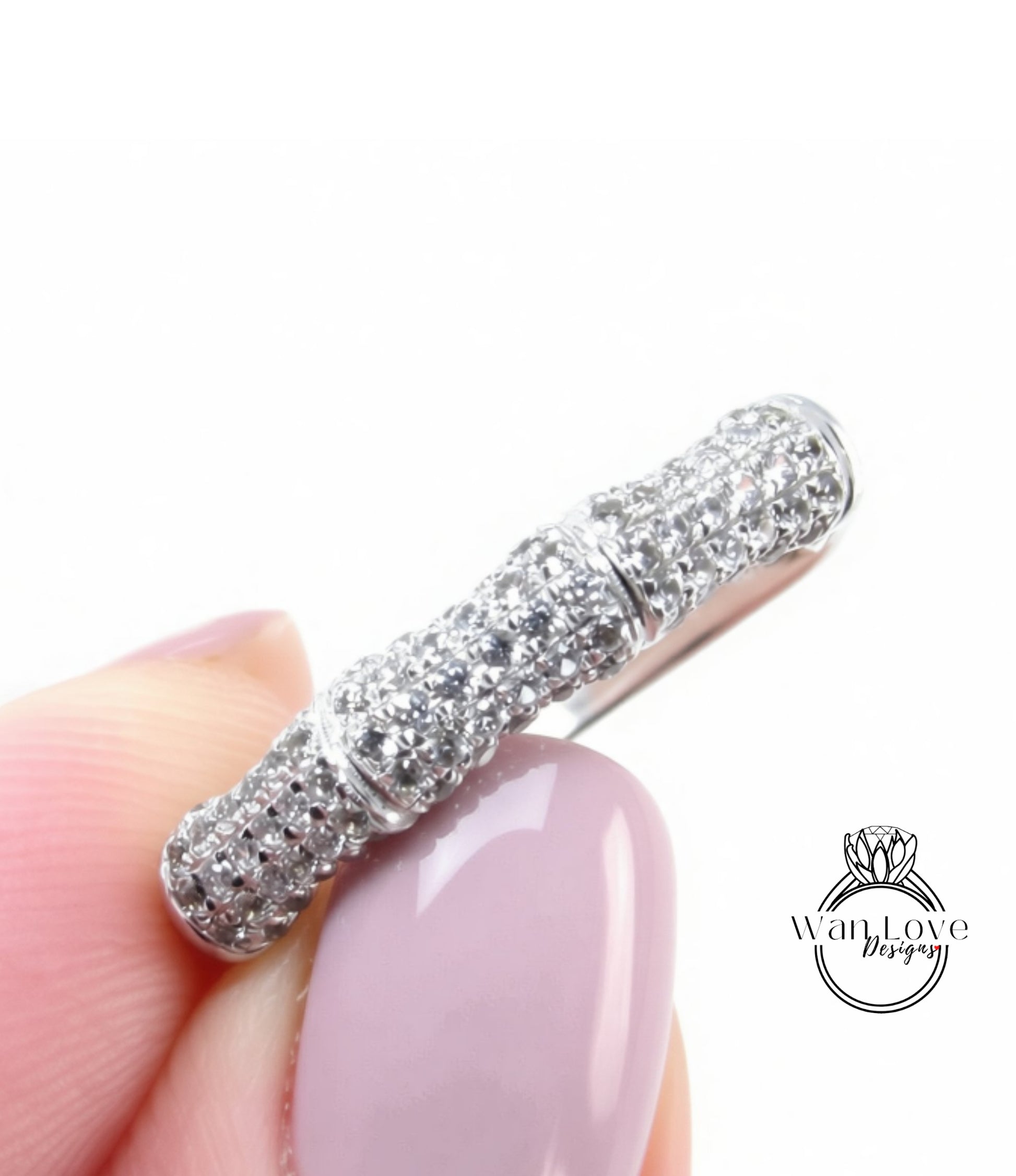 A close-up image of a person's hand holding a ring with a large, sparkling diamond band.