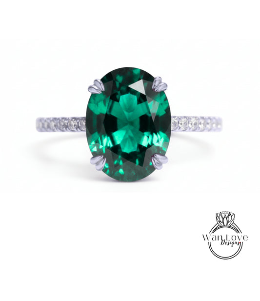 A large oval-shaped green gemstone, possibly a sapphire or emerald, set in a silver ring with a small diamond band.