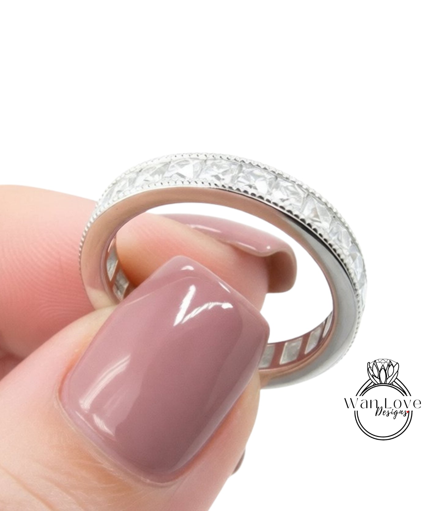A close-up of a person's hand holding a silver ring with a row of diamonds on the band.