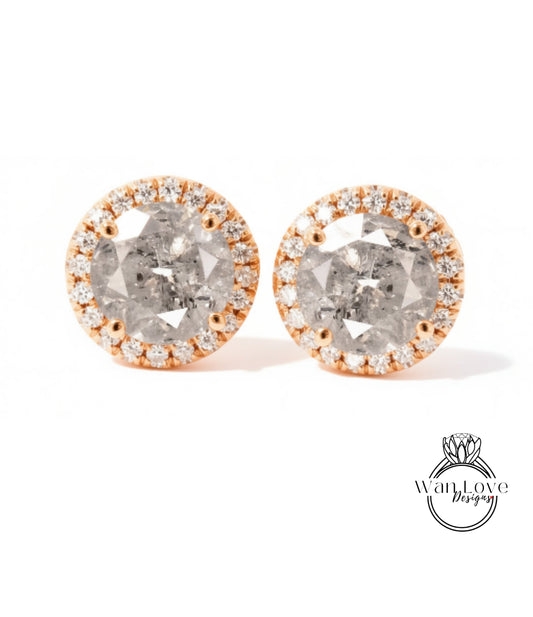 A pair of elegant earrings with a large, round diamond at the center, surrounded by a halo of smaller diamonds and set in a gold-toned metal.