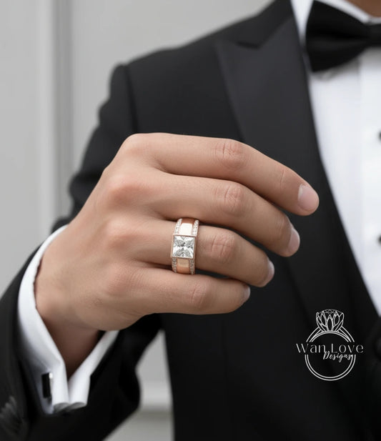 A close-up of a person's hand wearing a gold ring with a diamond, with a black suit jacket visible in the background.