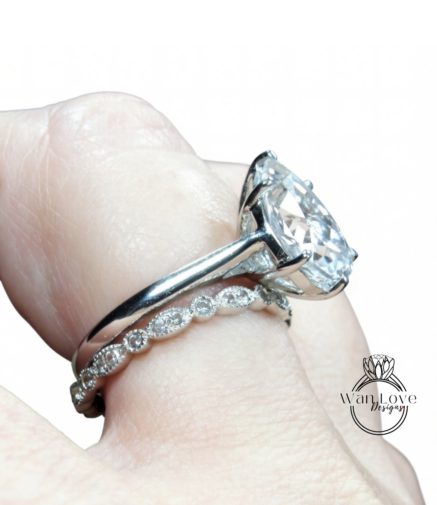 A close-up of a person's hand wearing a large diamond engagement ring with a delicate band.