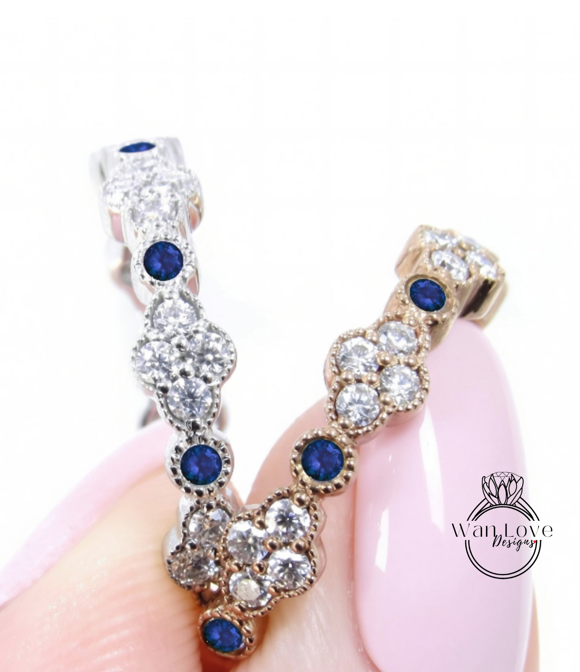 A close-up image of a person's hand holding a piece of jewelry with a combination of silver and gold elements, adorned with blue gemstones.
