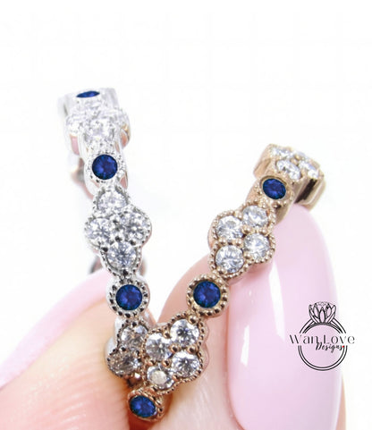 A close-up image of a person's hand holding a piece of jewelry with a combination of silver and gold elements, adorned with blue gemstones.