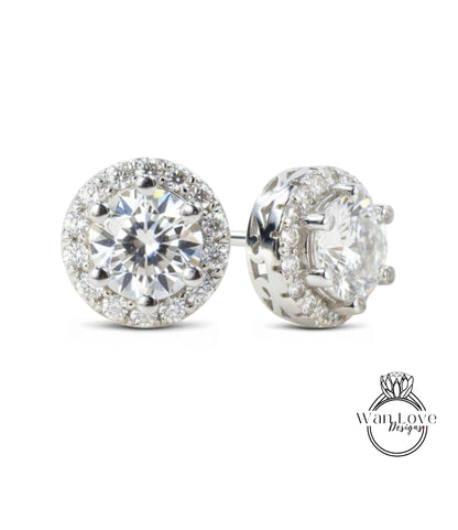 A pair of elegant earrings with a large, brilliant-cut diamond surrounded by smaller diamonds, set in a silver-toned metal.