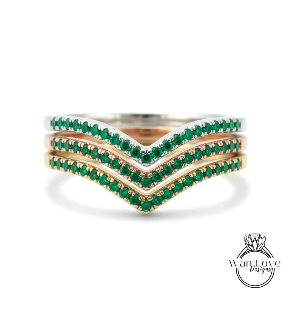 A ring with three concentric bands of green gemstones, likely emeralds, set in a silver or gold tone.