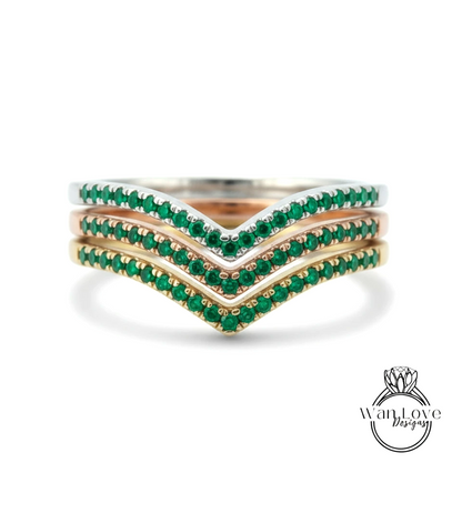 A ring with three concentric bands of green gemstones, likely emeralds, set in a silver or gold tone.