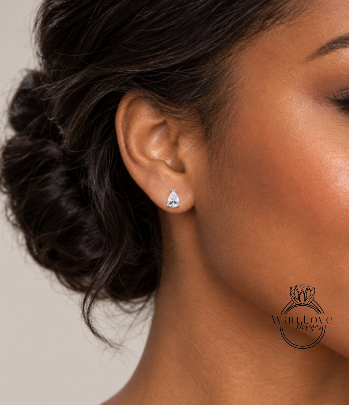 A close-up of a woman's ear with a diamond earring, featuring a small, clear gemstone.